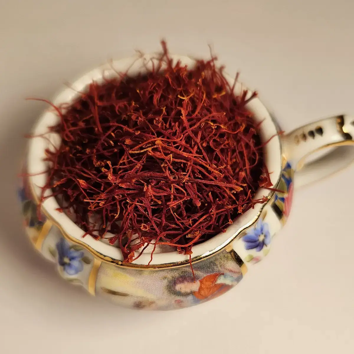 Vivid crimson saffron threads gathered in an antique gold-rimmed china cup.